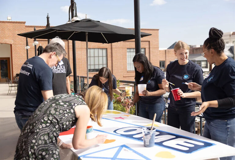 Group painting a large banner outdoors.