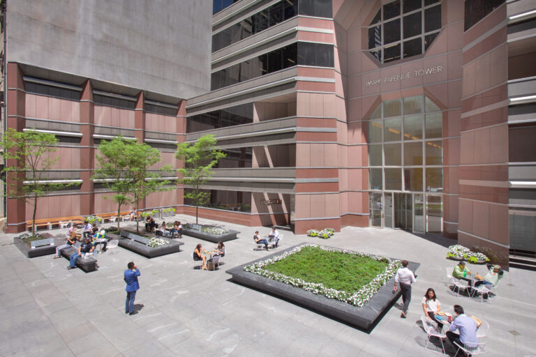 open plaza where people are seated at tables and on benches outside Park Avenue Tower