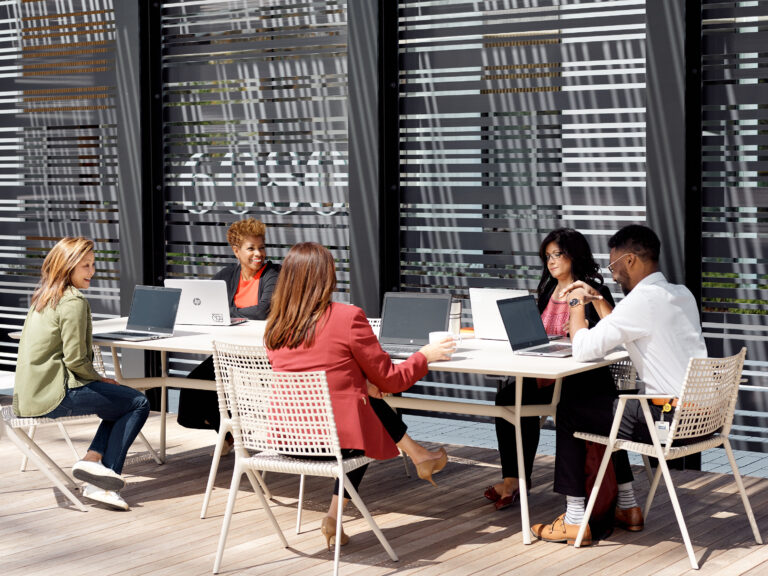 Outdoor meeting with laptops and drinks.